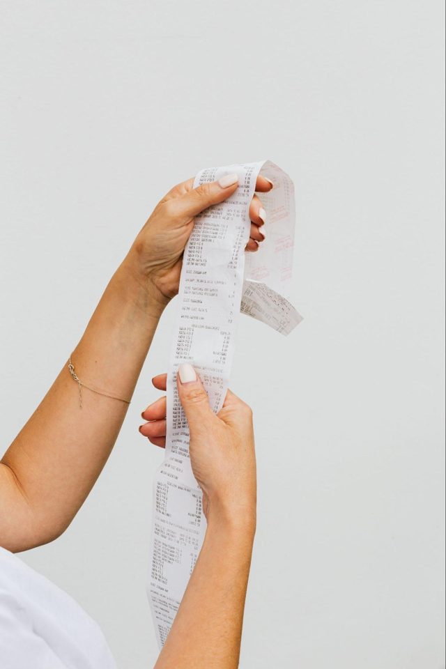 Two hands holding up a long paper receipt